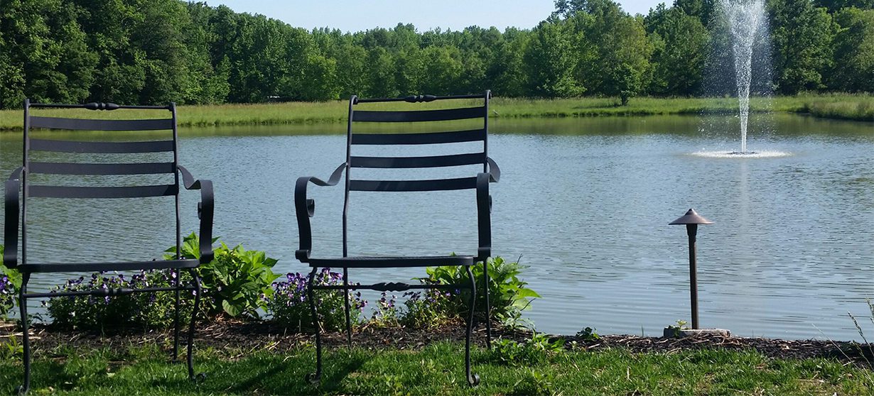 A chair sitting in the grass near water.