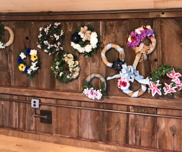 A wall with many different wreaths hanging on it.