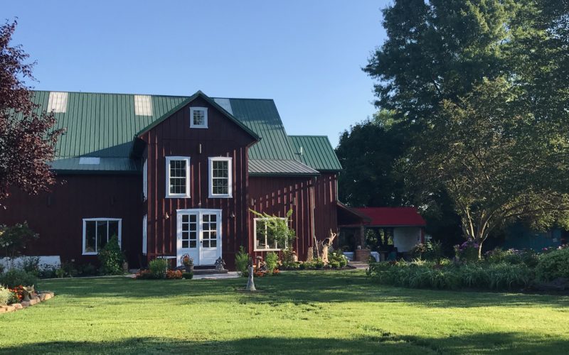 A large red house with green roof and lawn.