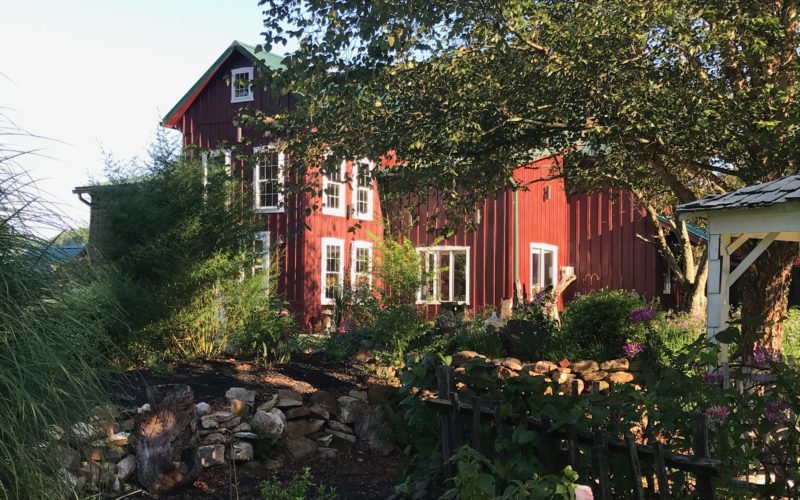 A red house with trees and bushes in the background.