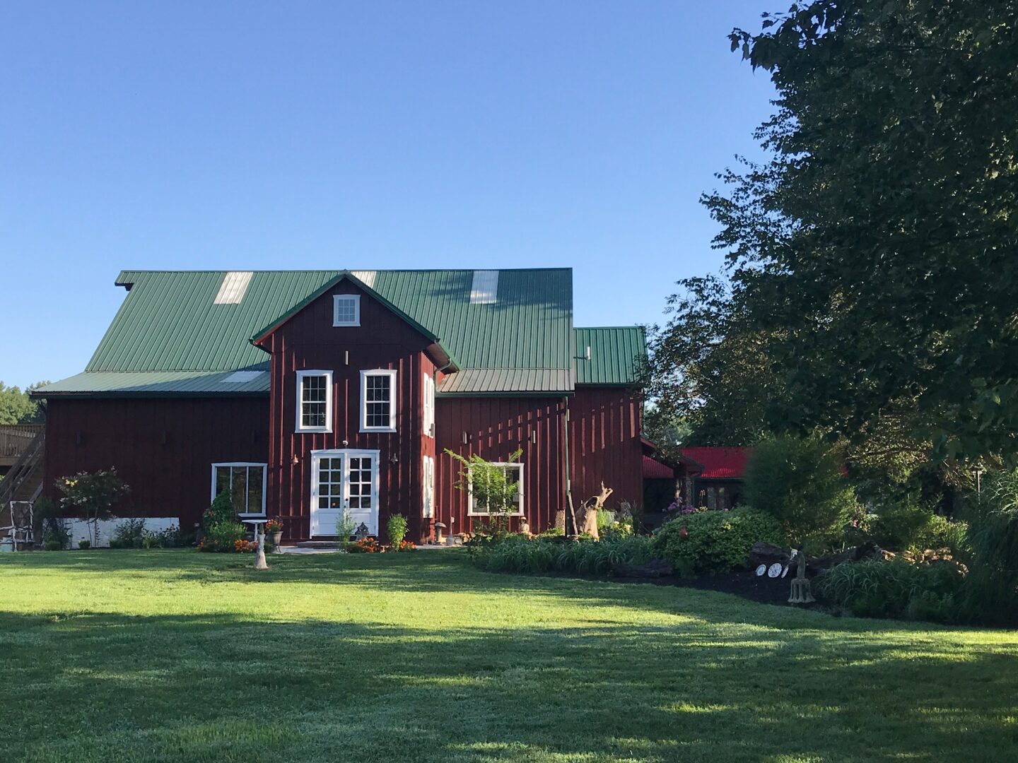 A large red house with green roof in the yard.