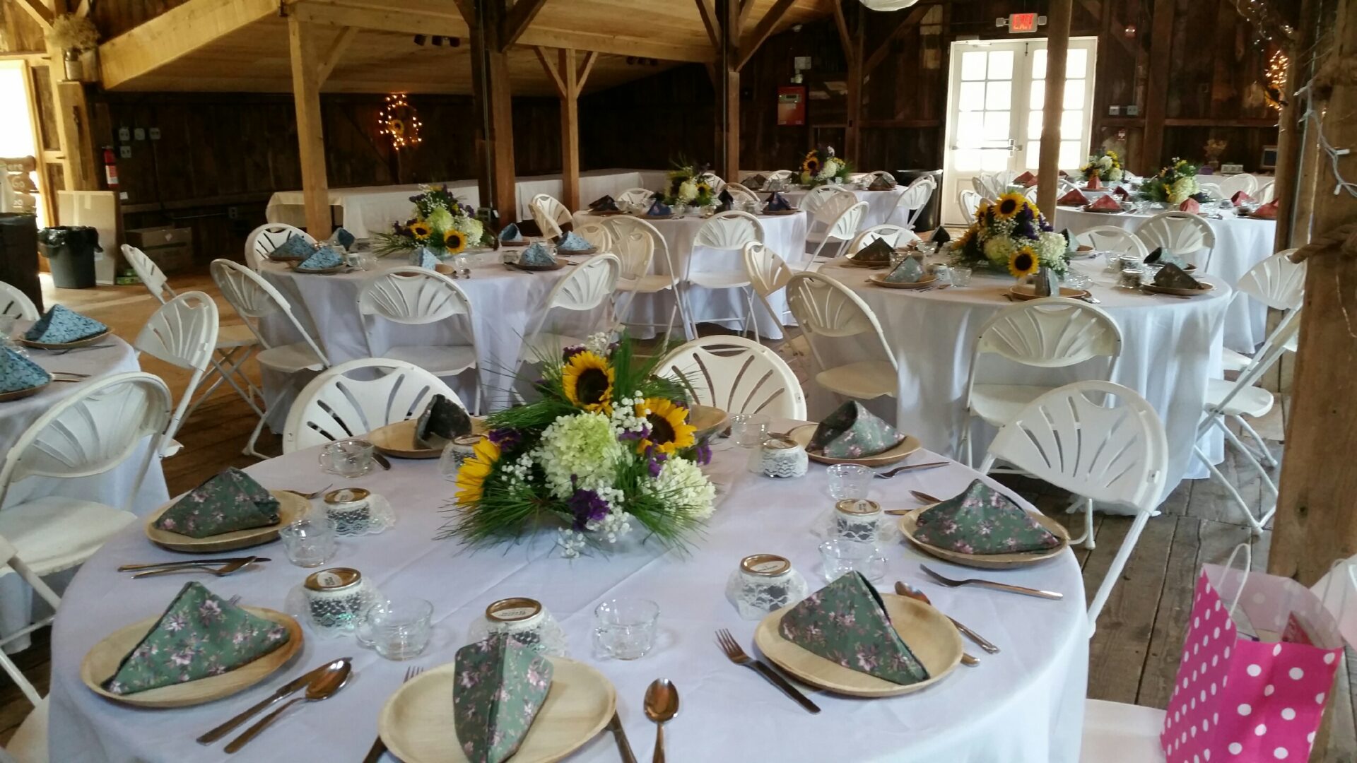 A table set for an event with white linens and yellow flowers.