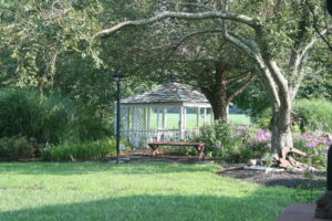 A gazebo in the middle of a park with trees.