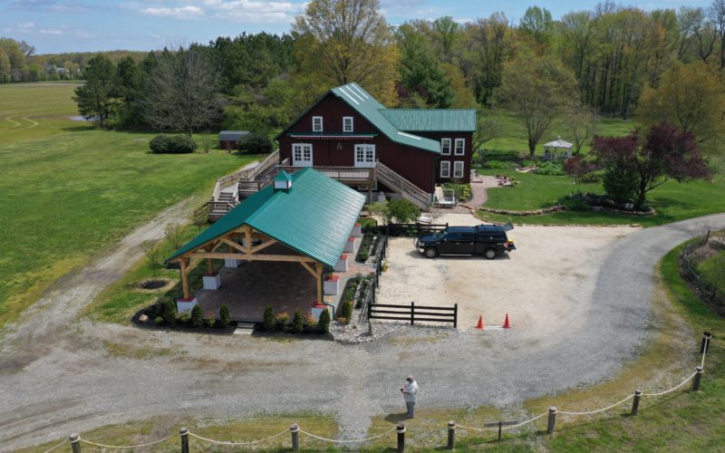 A barn with a green roof and a car parked in front of it.