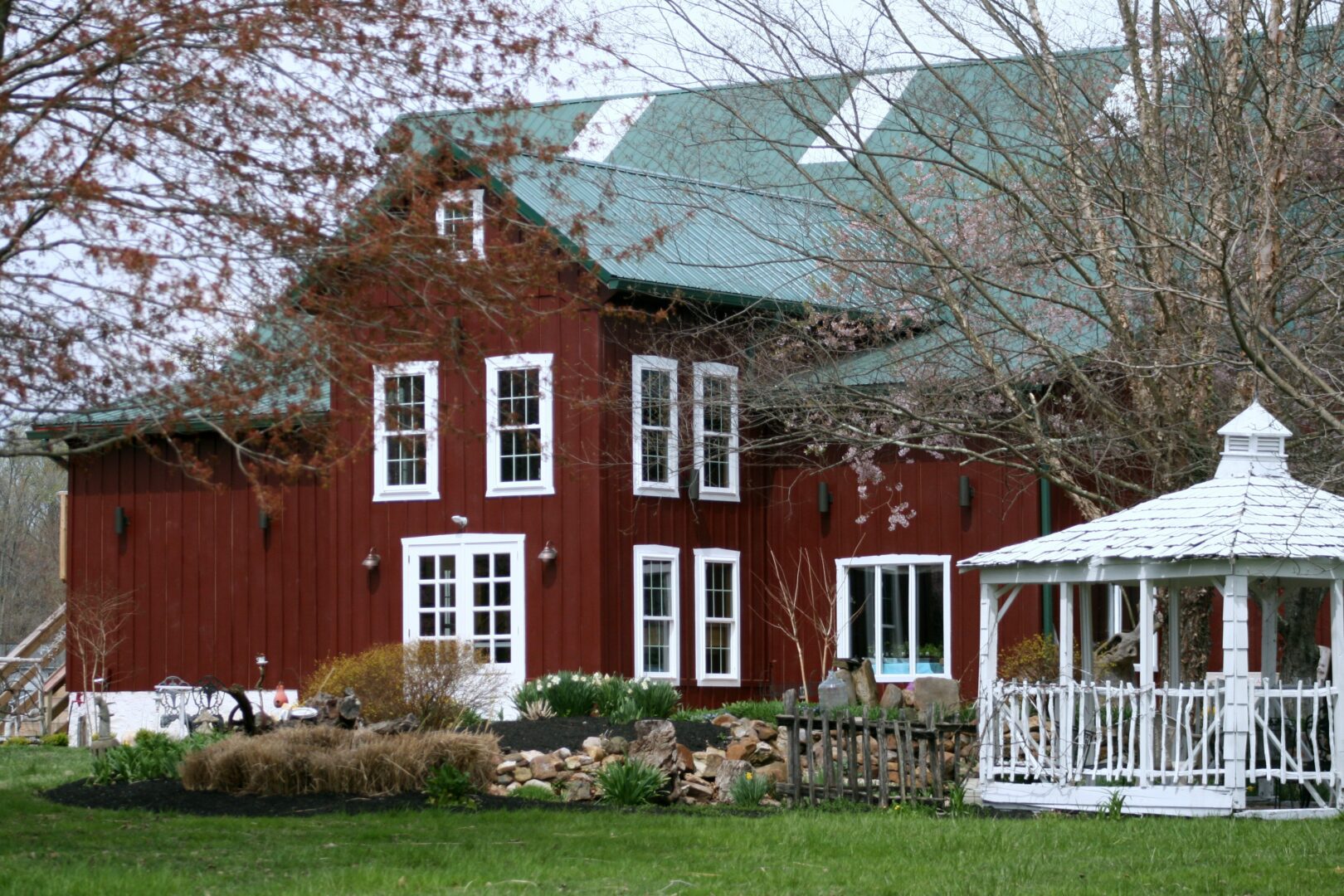 A red house with a porch and lawn in front of it.