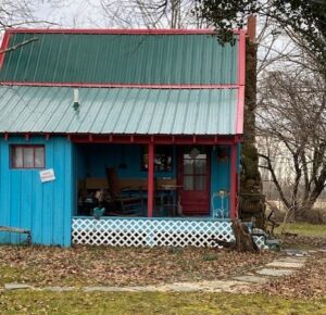 A blue house with red trim sitting on the side of a road.