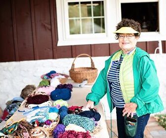 A woman standing next to a table with many items.