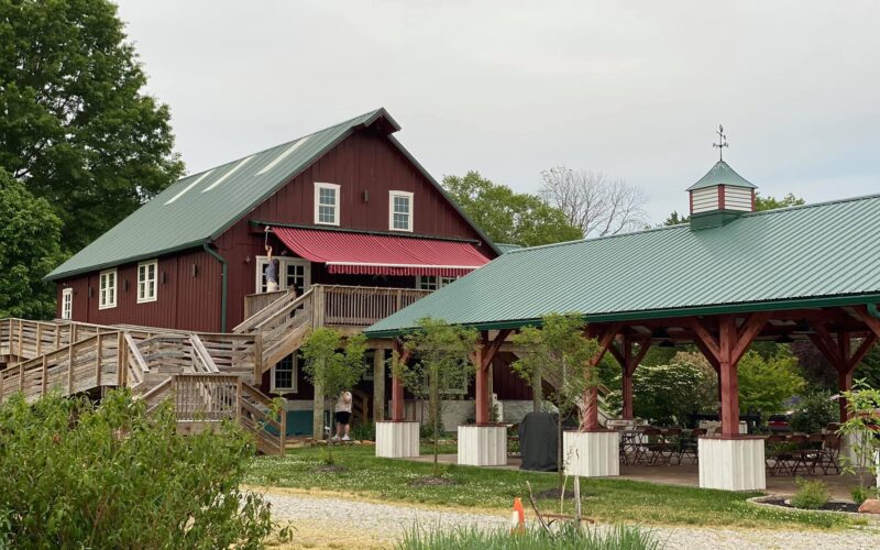 A red barn with a green roof and a gazebo.