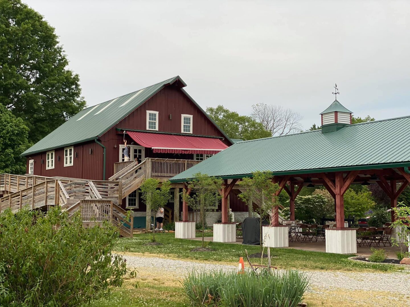 A red barn with a green roof and a gazebo.