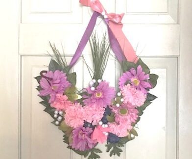 A pink and purple wreath hanging on the door.