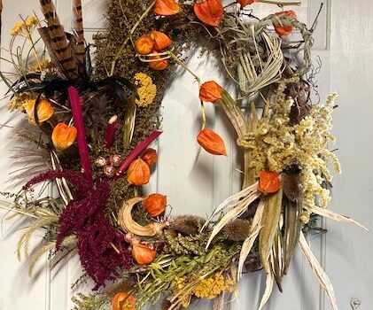 A wreath of dried flowers and feathers hanging on the door.