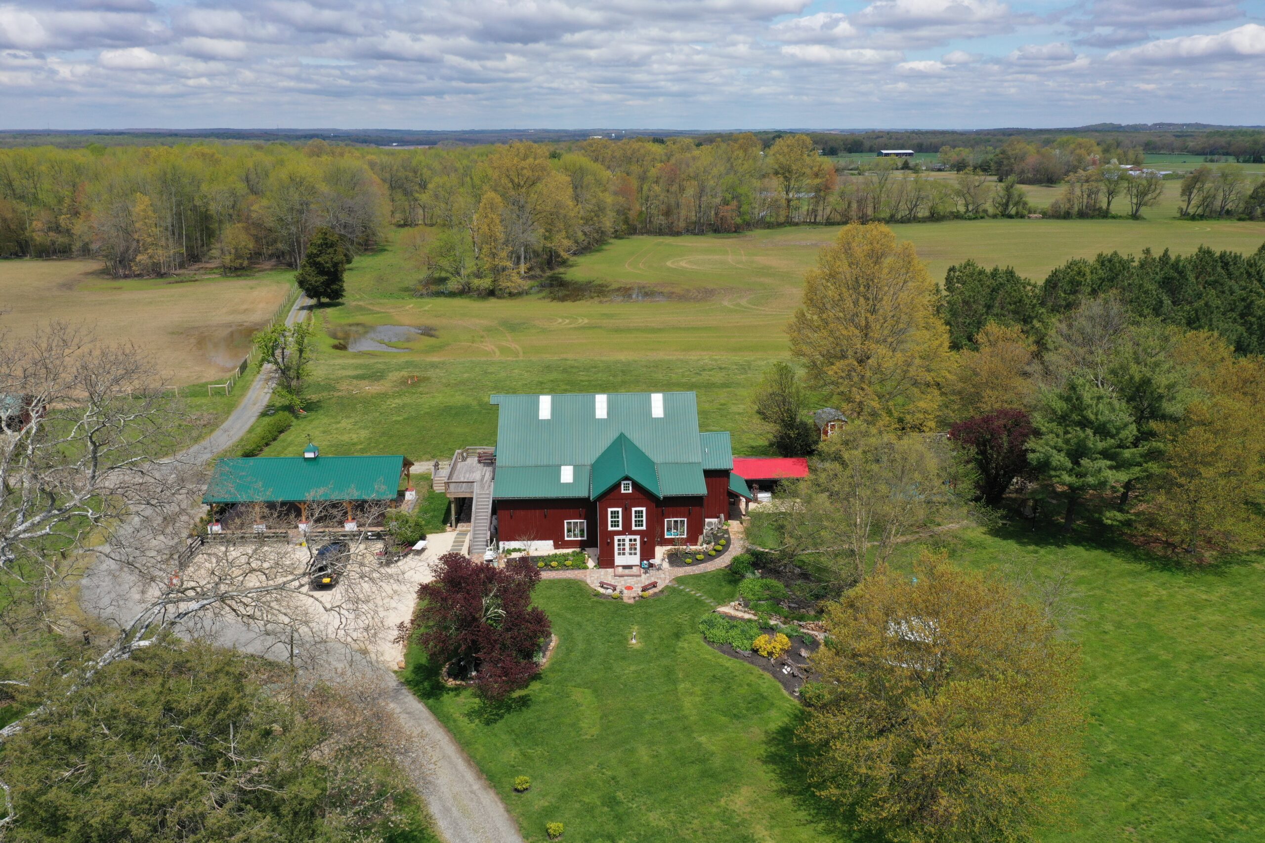 A large red house with green roof in the middle of a field.